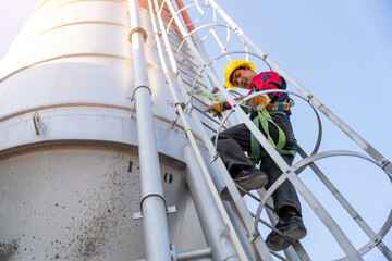 Close-up of a construction worker in a safety harness climbing a cement silo ladder, showing compliance with industrial safety regulations.