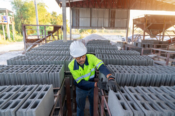A construction manager inspects rows of fresh concrete cinder blocks at a small building material...