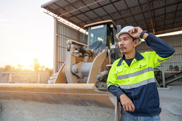 A construction manager stands next to a wheel loader, overseeing aggregate operations and industrial machinery at a ready-mix plant.
