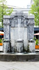 fountainhead. A classical stone water fountain sculpture in a town square, water flowing from its crevices. real-estate listings.
