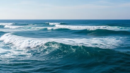 Fototapeta premium Expansive View of Dynamic Ocean Waves Rolling Towards the Shoreline Under a Clear Blue Sky, Capturing the Power and Serenity of the Sea