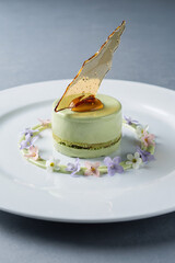 Dessert: green mousse cake with caramel shard and edible flowers.