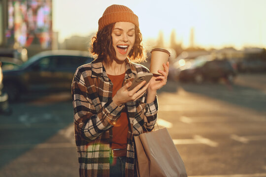 Woman with coffee and phone, smiling while shopping in urban sunlight at golden hour glow. Candid lifestyle portrait with authenticity, mindful living and emotional storytelling mood.