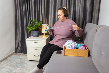 Adult Woman Knitting Yarn and Creating Handmade Items While Relaxing on a Sofa in the Comfort of Her Home