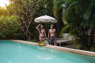 A man and a woman joyfully walking in front of a beautiful pool