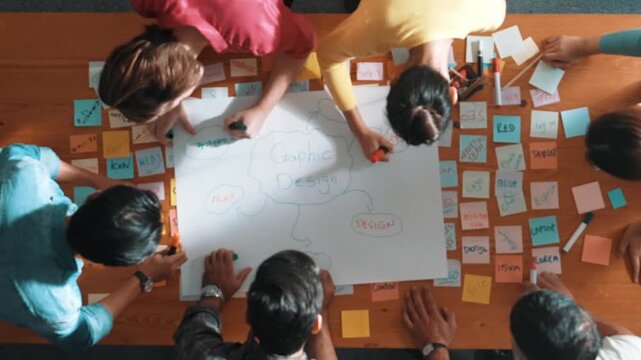 Top down view of manager writing and sharing idea by using mind map. Aerial view of smart business team working together and planning by writing in paper and drafting strategy with pencil. Symposium.