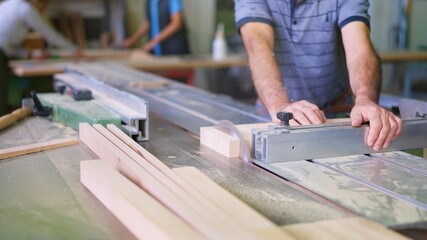 Carpenter cutting wood plank with circular saw in workshop