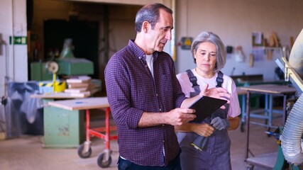 Senior carpenters discussing project using digital tablet in workshop
