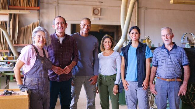 Diverse team of smiling factory workers standing in workshop