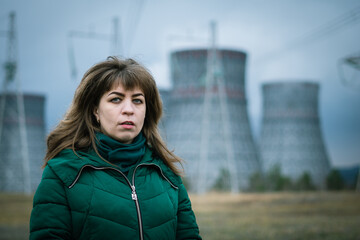 Obraz premium a girl on the background of a cooling tower of a nuclear power plant