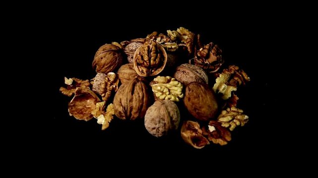 Close up shot of walnuts resting on a dark background, highlighting their rich texture and warm earthy tones.