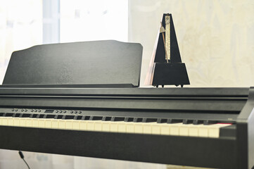 Mechanical metronome on modern electronic piano, symbolizing precision and rhythm in music