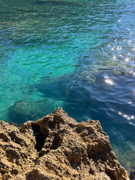 Mediterranean sea glittering clear water and rock.