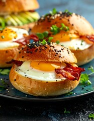 Close-up shot of delicious breakfast sandwiches with sunny-side-up eggs, crispy bacon, and toasted buns. Garnished with sesame seeds and herbs