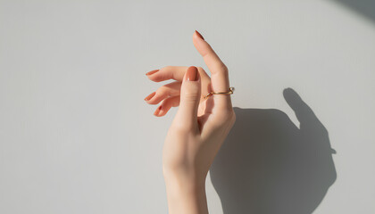 エレガントな女性の手元とベージュピンクのネイルとパールリング