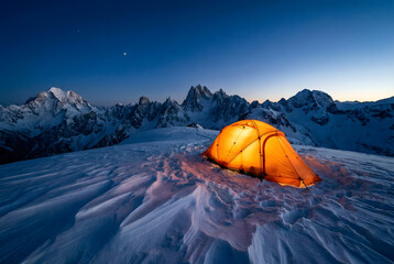 Illuminated orange tent on snowy mountain ridge at twilight camping