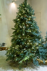 A festive Christmas tree display featuring sparkling ornaments, twinkling lights, and seasonal decorations. The tree is adorned with baubles, ribbons, garlands, and a bright star on top, creating a wa