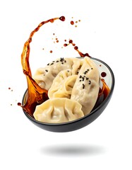 Close-up shot of several dumplings sitting in a black and white bowl, with a soy sauce splash in air