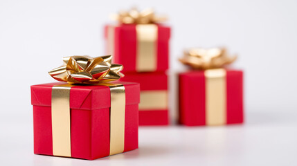 Stacked red gift boxes with golden ribbons arranged against a bright minimal background.
