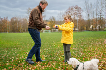 Fototapeta premium Little girl and father going for a walk with Maltese dog puppy. Happy child and pet.