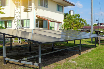 Ground-mounted solar panels are installed in front of a residential building, utilizing renewable energy to power the home. Depicts sustainable living and clean energy adoption.