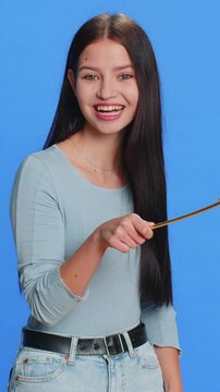 Magician witch young woman gesturing with magic wand fairy stick, making wish come true, casting magician spell, advertising holidays sale discount. Pretty girl isolated on blue studio background