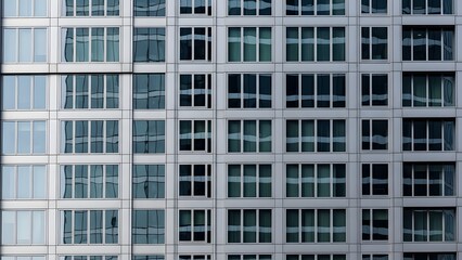 Fototapeta premium Sleek modern building facade with grid of reflective glass windows, showcasing urban architecture
