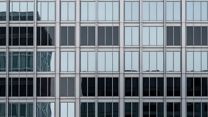 Modern glass facade with reflective windows creating a geometric grid pattern on an urban skyscraper