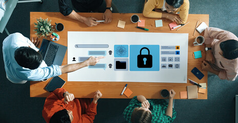 A diverse team collaborates in an office setting, analyzing cybersecurity solutions through a digital interface displayed on a table, fostering discussion and innovation. Gantry