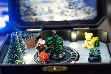 A beautifully crafted Christmas music box featuring reindeer, Santa figures, festive dolls, and a rotating carousel. The intricate design, warm lighting, and nostalgic holiday motifs create a magical 