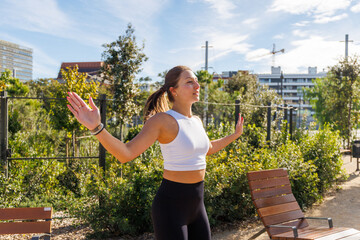 Female outdoor athlete stretching legs after workout session on park concrete path wearing sport leggings and top