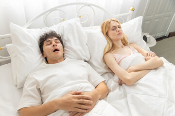 Frustrated women lying in bed next to snoring man, showing relationship issues and sleep disturbance. Ideal for concepts of sleep problems, snoring and couple conflict at night.