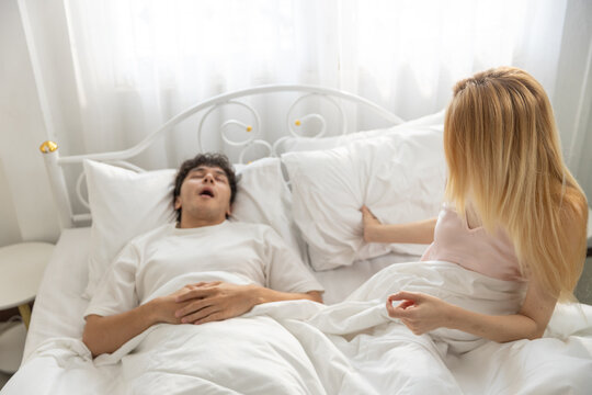 Frustrated women lying in bed next to snoring man, showing relationship issues and sleep disturbance. Ideal for concepts of sleep problems, snoring and couple conflict at night. - Powered by Adobe