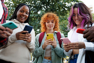 Group of diverse students using smartphones outdoors, browsing internet and social media