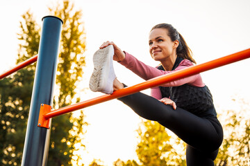 Fototapeta premium Smiling woman doing warm up stretching exercise outdoors.