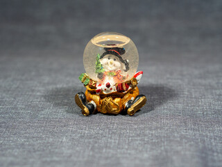 Snow globe with snowman and gift bag. Christmas decor element. Glass snow ball on a shelf or on a table