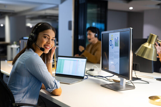 Diverse coworkers handling customer calls at modern open-plan office using headsets and monitors