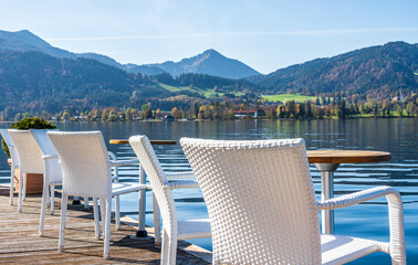 Relaxing seating arrangement by the calm lake with white chairs and a round pot in the morning sunlight