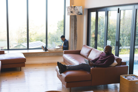 Brown leather sectional sofa is framing living room space overlooking pool and greenery, copy space