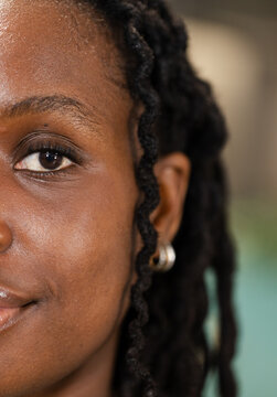 Left half of female face showing skin texture, twisted locs and silver hoop in studio