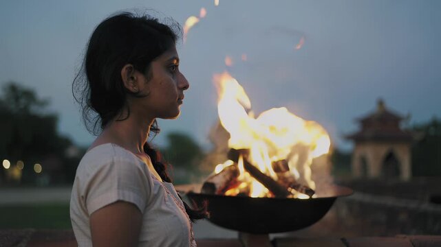 Profile of a woman holding a sacred fire for a traditional ceremony. Spiritual ritual at dusk with burning flames. Cinematic slow motion footage