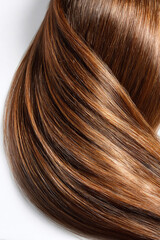 Fototapeta premium Glossy, flowing strands of brown hair cascade elegantly against a clean white background, showcasing the beauty and texture of healthy hair in a captivating visual display