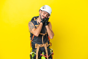 Young caucasian rock climber man isolated on yellow background making sleep gesture in dorable expression