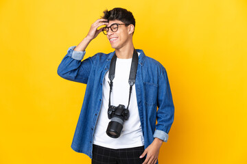 Young photographer man over isolated yellow background smiling a lot