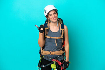 Young Italian rock-climber woman isolated on blue background pointing to the side to present a product
