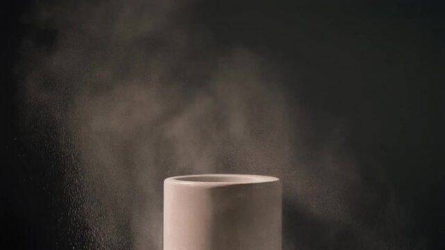 A ceramic cylindrical object expels light vapor against a dark background, creating dynamic movement