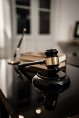 A polished wooden gavel resting on a glossy black surface illuminated by soft directional light, symbolizing justice, legal authority, courtroom decisions, professional