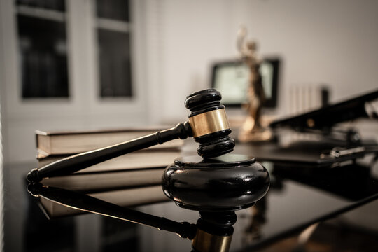 A polished wooden gavel resting on a glossy black surface illuminated by soft directional light, symbolizing justice, legal authority, courtroom decisions, professional