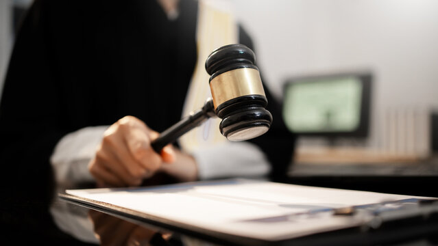 A judge raises gavel in courtroom, poised to deliver formal ruling, global justice, international law, digital regulation, modern legal authority across criminal, trade, cyber, humanitarian fields.