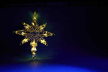 Illuminated Star. A glowing star ornament shines against a dark blue background.